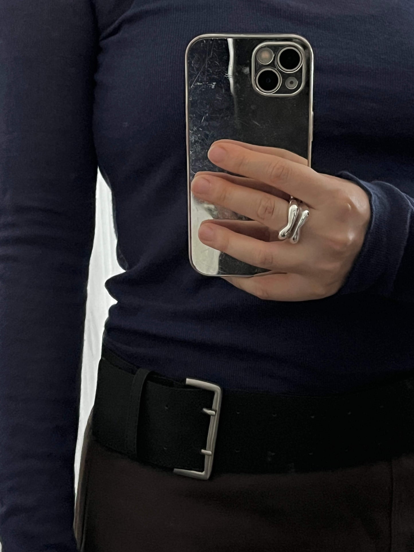 mirror selfie featuring a hand wearing the handmade sculptural Silver Lining ring in an organic shape with a slit in the middle by LEAP STUDIO.