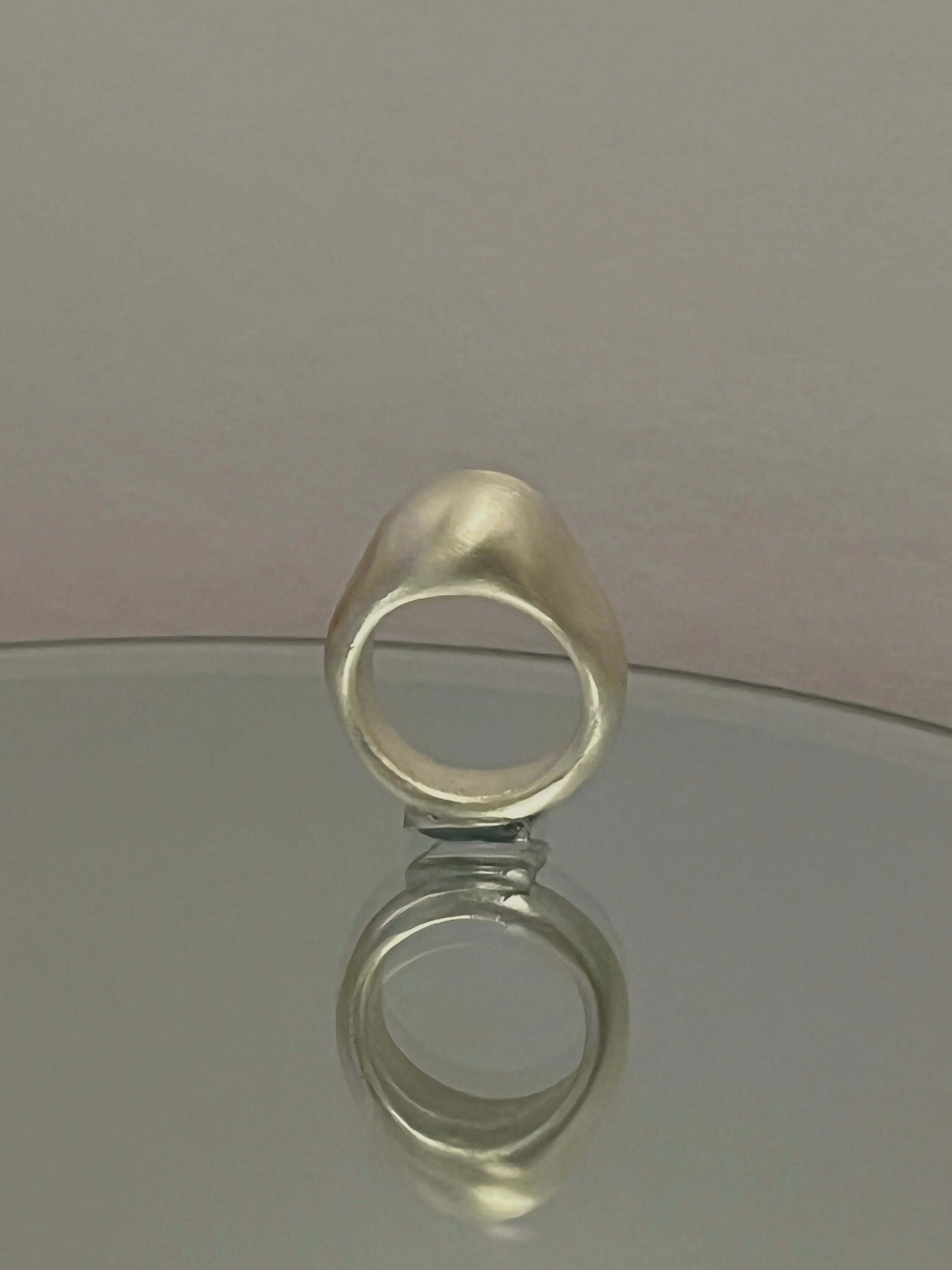 Sculptural Orb Ring standing upright on mirror, reflecting its smooth dome shape and handcrafted silver form.