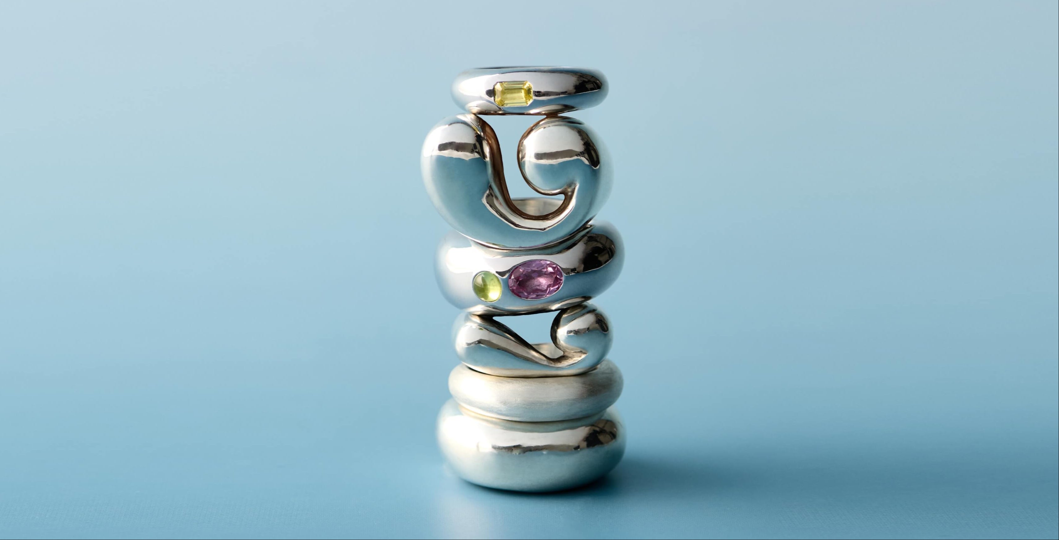 Stack of handmade sculptural silver rings with colorful gemstones on a light blue background – LEAP STUDIO jewelry collection banner