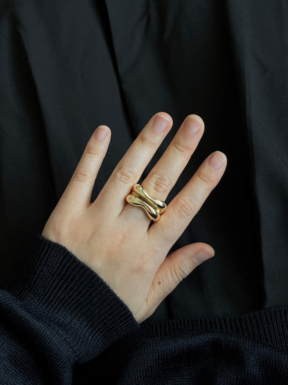 Close-up of hand modeling the handmade 18k gold sculptural Silver Lining ring, featuring organic shapes and a slit in the middle, by LEAP STUDIO.